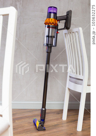 Handheld vacuum cleaner leaned against chair in room 103632275