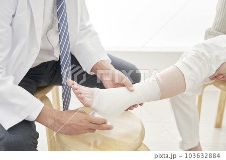 足首に包帯を巻く医者　顔無し 103632884