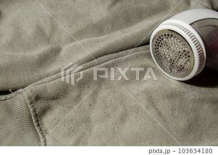 Anti-pilling razor. Device for shaving pellets clothes. Anti-Plush fabric Shaver. Electric portable sweater pill defuzzer Lint remover from acrylic or wool sweater. Sustainability lifestyle fashion Anti-pilling razor. Device for shaving pellets clothes. Anti-Plush fabric Shaver. Electric portable sweater pill defuzzer Lint remover from acrylic or wool sweater. Sustainability lifestyle fashion 103634180