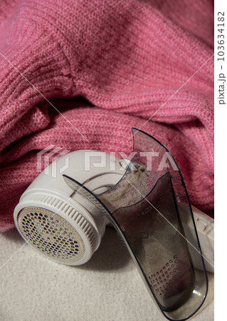 Anti-pilling razor. Device for shaving clothes. Anti-Plush fabric Shaver. Electric portable sweater pill defuzzer Lint remover from pink acrylic or wool sweater. Electric device fabric shaver after Anti-pilling razor. Device for shaving clothes. Anti-Plush fabric Shaver. Electric portable sweater pill defuzzer Lint remover from pink acrylic or wool sweater. Electric device fabric shaver after 103634182