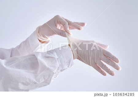 The medical worker puts on latex gloves. The medical worker puts on latex gloves. 103634285