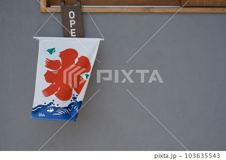 夏の風物詩の氷の旗が風に煽られて漆喰壁の前で揺れている風景 103635543