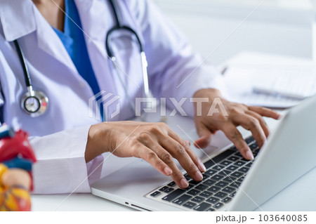 Doctor consult patient on laptop with anatomical model of human heart Cardiologist supports the heart Online doctor appointment.. Doctor consult patient on laptop with anatomical model of human heart Cardiologist supports the heart Online doctor appointment.. 103640085