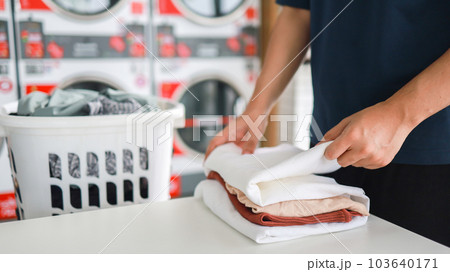 House husband with Basket and dirty laundry washed clothing in laundry room interior. washing machine at laundry business store House husband with Basket and dirty laundry washed clothing in laundry room interior. washing machine at laundry business store 103640171