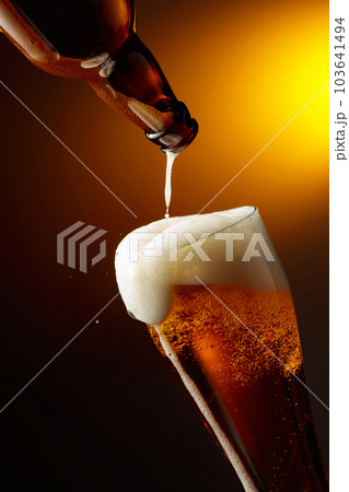 Pouring beer into a tall glass. 103641494