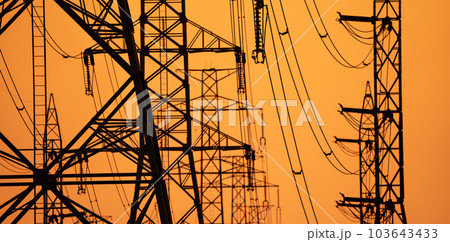 High voltage electric transmission tower. High voltage power lines on electric pylon against a sunset sky. Electrical infrastructure. Energy crisis. Electric power distribution. Energy distribution. 103643433