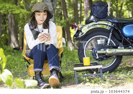 バイク女子イメージ 湖にバイクでツーリングに来てチェアリングをしながらスマホを見る女性 バイク女子イメージ 湖にバイクでツーリングに来てチェアリングをしながらスマホを見る女性 103644374