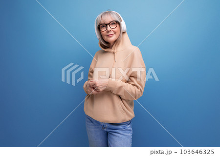 stylish 60s granny with gray hair learns again and listens to music with headphones on studio stylish 60s granny with gray hair learns again and listens to music with headphones on studio 103646325