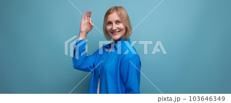 close-up of a mature woman in a blue shirt with an idea on a blue background with copy space 103646349