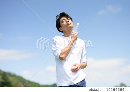 ペットボトルの水で首筋を冷やす若い男性 ペットボトルの水で首筋を冷やす若い男性 103646644