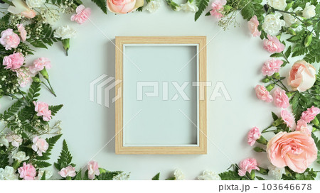 Blank wooden picture frame with pink rose, carnation and fern leaves on white background. Spring floral background 103646678