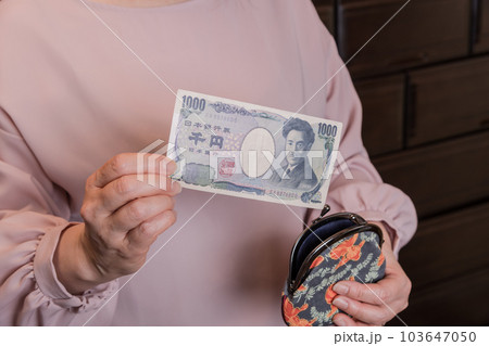 【がま口から1000円札を出す主婦】 103647050