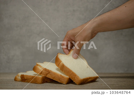 食パンと手　スライスした食パンを手に取る男性の手　 103648764