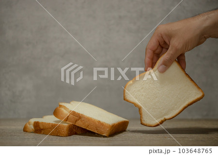 食パンと手　スライスした食パンを手に取る男性の手　 103648765