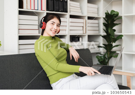 Young relaxed smiling pretty woman relaxing sitting on sofa at home. Female feeling joy enjoying with music on cozy couch Young relaxed smiling pretty woman relaxing sitting on sofa at home. Female feeling joy enjoying with music on cozy couch 103650543