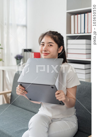 Young relaxed smiling pretty woman relaxing sitting on sofa at home. Female feeling joy enjoying with laptop on cozy couch Young relaxed smiling pretty woman relaxing sitting on sofa at home. Female feeling joy enjoying with laptop on cozy couch 103650550