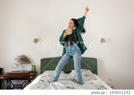 Young Caucasian happy woman is dancing and singing with hairbrush in bed. Funny enjoy in bedroom. Concept of dance and vocals learning Young Caucasian happy woman is dancing and singing with hairbrush in bed. Funny enjoy in bedroom. Concept of dance and vocals learning 103651242