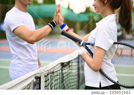 Shot of two young tennis players giving each other high five over net at tennis court Shot of two young tennis players giving each other high five over net at tennis court 103651581
