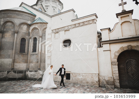 A loving wedding couple are walking back along the streets of the city of Lviv A loving wedding couple are walking back along the streets of the city of Lviv 103653999