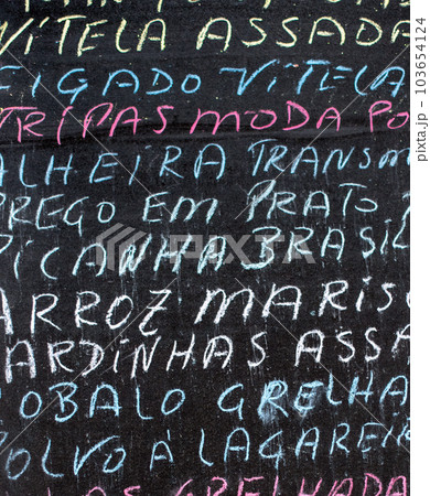 Detail of a portuguese menu written in multicolored chalk on a black chalkboard Detail of a portuguese menu written in multicolored chalk on a black chalkboard 103654124