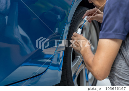 車についた擦り傷を自分で修理しようとしている中高年男性 車についた擦り傷を自分で修理しようとしている中高年男性 103656167