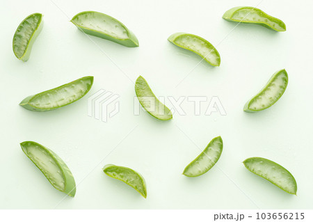 Top view of fresh aloe vera leaf slice with water drops over green background. Gel from the leaves of aloe plants used for medicine and skin care. 103656215