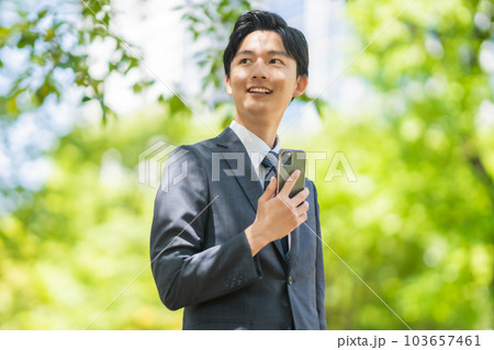 スーツ姿で外回りをする若いビジネスマン スーツ姿で外回りをする若いビジネスマン 103657461