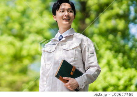 新緑中手帳を持って歩くエンジニア 103657469