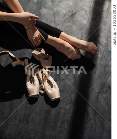 Faceless ballerina sits on the floor and puts on pointe shoes. Faceless ballerina sits on the floor and puts on pointe shoes. 103658003