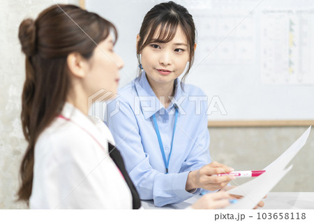 コーヒーを飲みながら打ち合わせする若い女性 103658118