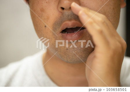 手を口に添えて内緒話をしている男性 103658501