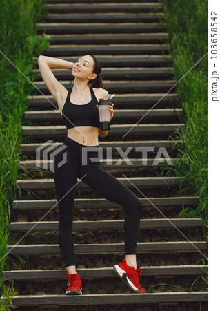 Pretty lady training in a summer city. Brunette doing yoga. Girl in a sportsuit. 103658542