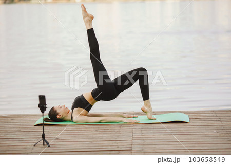 Pretty lady training in a summer park. Brunette doing yoga. Girl shoots a blog. 103658549
