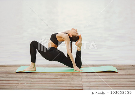 Pretty lady training in a summer park. Brunette doing yoga. Girl in a sportsuit. 103658559