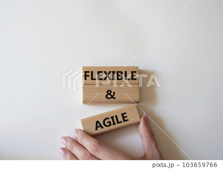 Flexible and agile symbol. Concept word Flexible and agile on wooden blocks. Beautiful white background. Businessman hand. Business and Flexible and agile concept. Copy space 103659766
