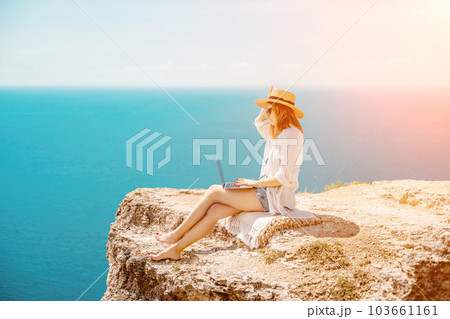 Freelance woman working on a laptop by the sea, typing away on the keyboard while enjoying the beautiful view, highlighting the idea of remote work. Freelance woman working on a laptop by the sea, typing away on the keyboard while enjoying the beautiful view, highlighting the idea of remote work. 103661161