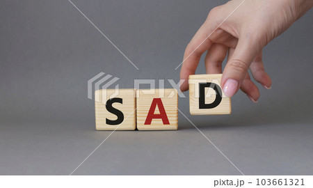 Sad symbol. Wooden cubes with words Sad. Businessman hand. Beautiful grey background. Business and Sad concept. Copy space. Sad symbol. Wooden cubes with words Sad. Businessman hand. Beautiful grey background. Business and Sad concept. Copy space. 103661321