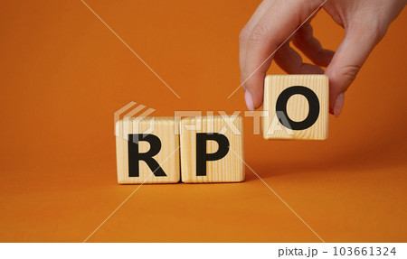 RPO - Recruitment Process Outsourcing symbol. Wooden cubes with words RPO. Businessman hand. Beautiful orange background. Business and RPO concept. Copy space. 103661324