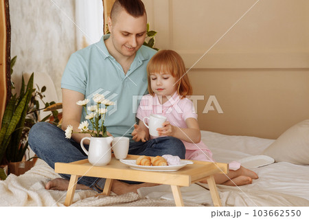 Father and daughter have breakfast in bed in the morning Father and daughter have breakfast in bed in the morning 103662550