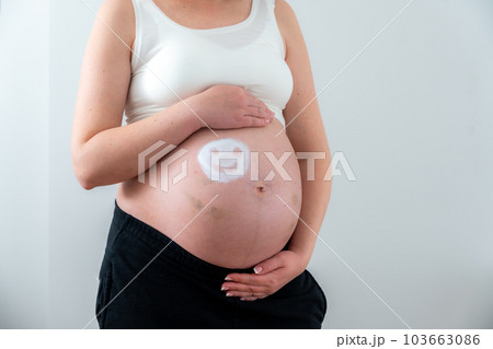 White emoticon on the girl's pregnant belly as a symbol of happiness 103663086