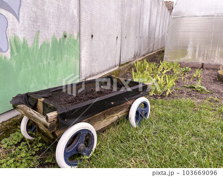 a small decorative cart in the garden in early spring 103669096