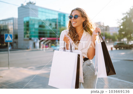 Fashion woman with shopping bags walking around city after shopping. Sale, lifestyle concept. 103669136