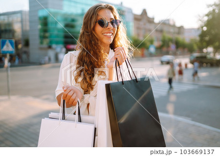 Fashion woman with shopping bags walking around city after shopping. Sale, lifestyle concept. Fashion woman with shopping bags walking around city after shopping. Sale, lifestyle concept. 103669137