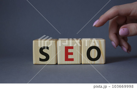 SEO - Search Engine Optimization symbol. Wooden blocks with words SEO. Businessman hand. Beautiful grey background. Business and SEO concept. Copy space. 103669998
