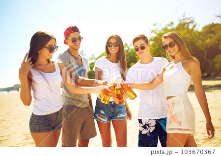 Group of friends hanging out with beer at the beach. Excellent sunny weather. Beautiful figures. 103670367