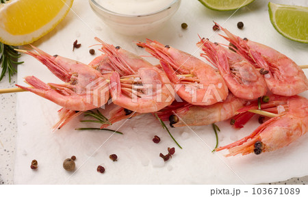 Shrimps strung on wooden sticks, soy sauce and spices on a white table, top view 103671089