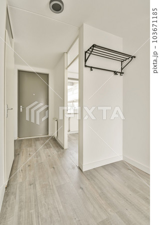 an empty room with white walls and wood flooring, there is a door leading to the left side of the room 103671185