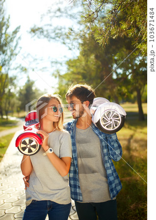 Young man and woman riding on the Hoverboard in the park. content technologies. a new movement. Young man and woman riding on the Hoverboard in the park. content technologies. a new movement. 103671484