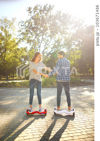 Young man and woman riding on the Hoverboard in the park. content technologies. a new movement. Young man and woman riding on the Hoverboard in the park. content technologies. a new movement. 103671486