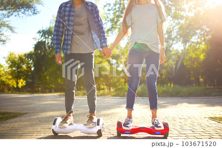 Legs of man and woman riding on the Hoverboard together outdoor. Active lifestyle technology future. Legs of man and woman riding on the Hoverboard together outdoor. Active lifestyle technology future. 103671520